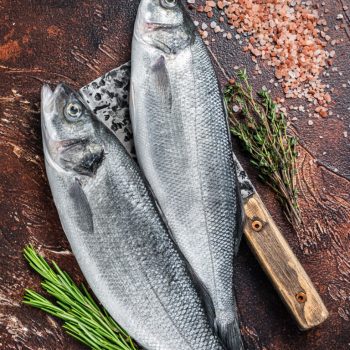 Seabass or sea bass fresh raw fish on a cleaver with salt and he