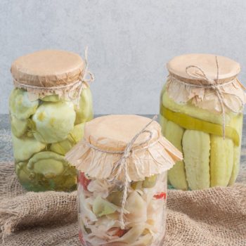 Three jars full of salty vegetables on sackcloth