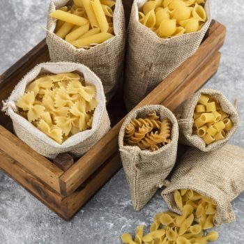 Pasta varieties in rustic basket inside a wooden tray