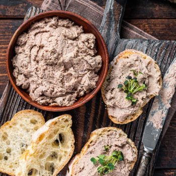 Toasts with Duck pate Rillettes de Canard on wooden board. Dark